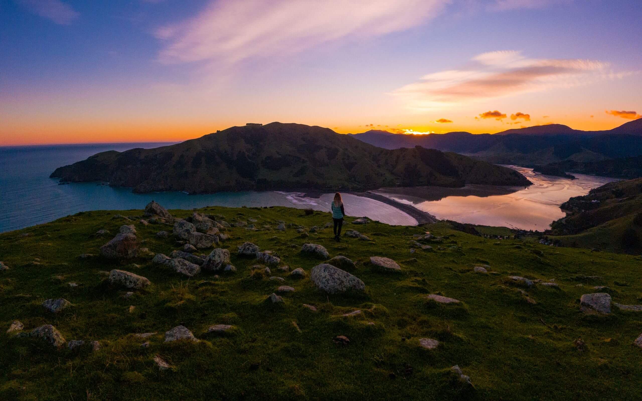 Catch the golden hour at Cable Bay, where the sky lights up over turquoise waters, rocky outcrops, and sweeping coastal views.