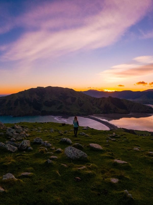 Catch the golden hour at Cable Bay, where the sky lights up over turquoise waters, rocky outcrops, and sweeping coastal views.