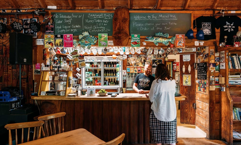 The Mussel Inn is a rustic, beloved spot known for its craft beers, live music, and laid-back vibe, nestled in the heart of Golden Bay.